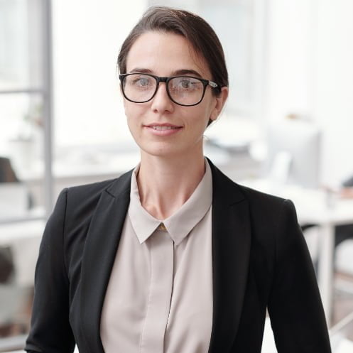 A business woman in glasses standing in an office focusing on automation integration.