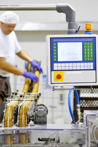 A man performing automation services and repairs on a machine in a factory.