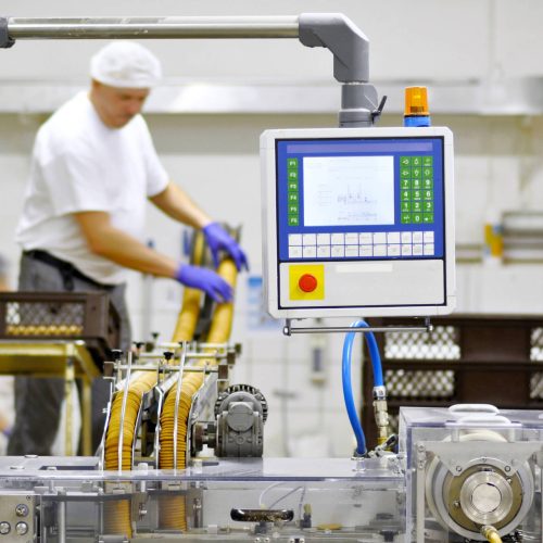 A man performing automation services and repairs on a machine in a factory.