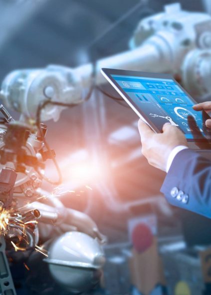 A man in a suit is using a tablet for industrial automation in a factory.