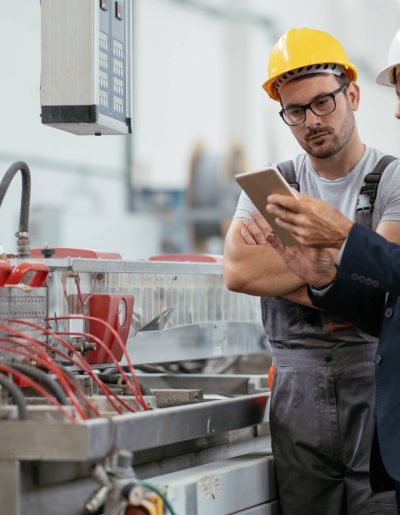 Two men in hard hats using factory automation technology for repairs.